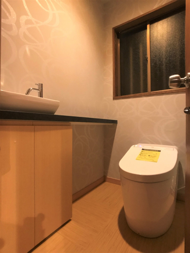 Foto på ett mellanstort orientaliskt svart toalett, med släta luckor, skåp i mellenmörkt trä, en toalettstol med hel cisternkåpa, vita väggar, bambugolv, bänkskiva i akrylsten, beiget golv och ett fristående handfat
