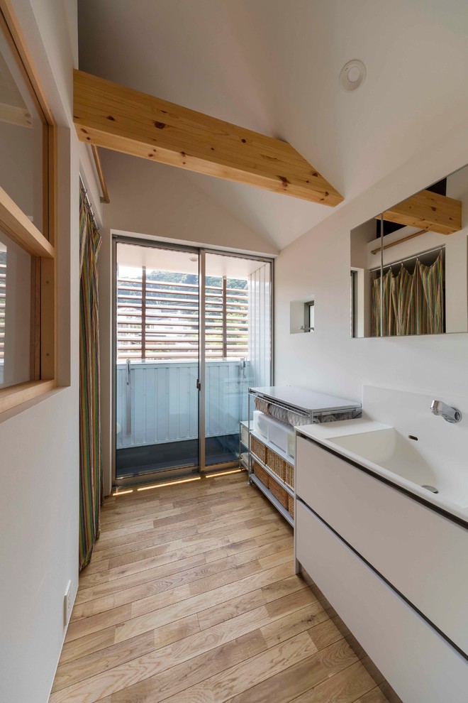 Immagine di un bagno di servizio etnico con ante lisce, ante bianche, pareti bianche, parquet chiaro, lavabo integrato e pavimento beige