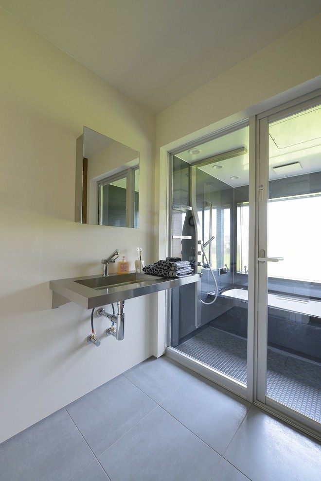 Exempel på ett industriellt toalett, med vita väggar, betonggolv, ett väggmonterat handfat, bänkskiva i rostfritt stål och grått golv