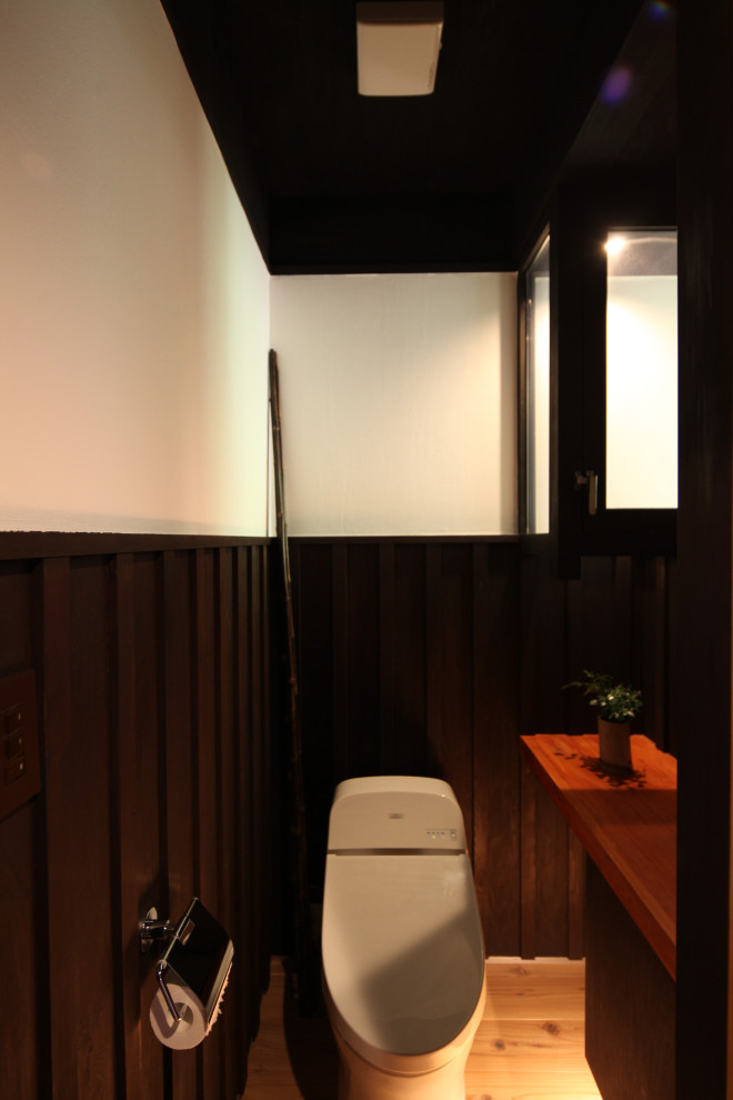 Réalisation d'un WC et toilettes chalet de taille moyenne avec WC à poser, un mur blanc, un sol en bois brun, poutres apparentes et boiseries.