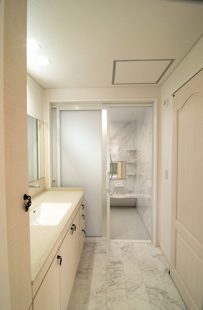 Ispirazione per un bagno di servizio stile shabby con ante lisce, ante bianche, pareti bianche, pavimento in marmo, lavabo integrato e pavimento grigio
