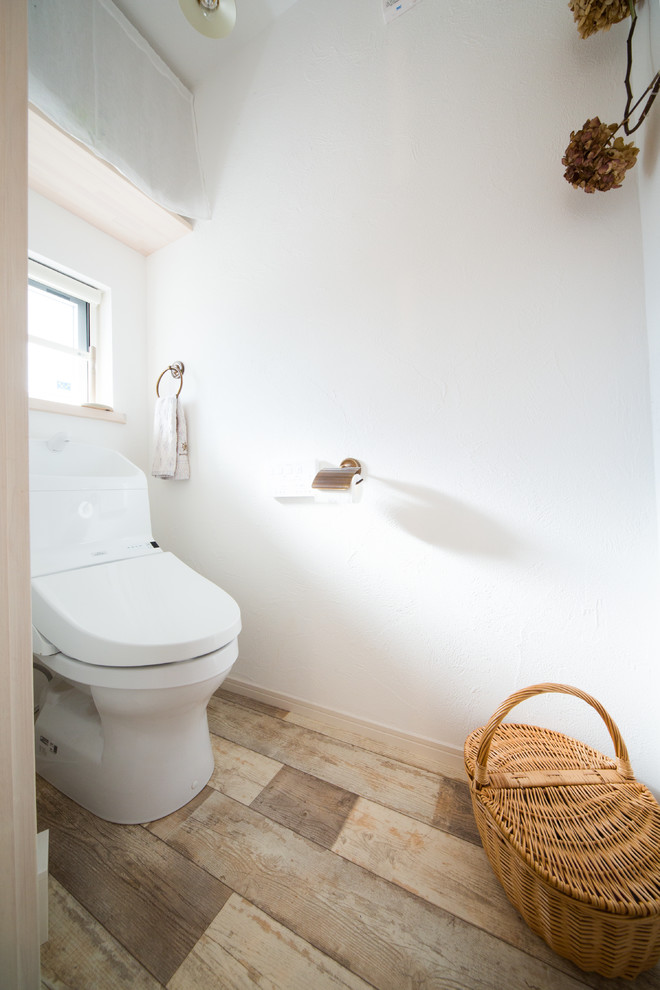 Foto di un bagno di servizio scandinavo con pareti bianche, pavimento in legno massello medio e pavimento marrone