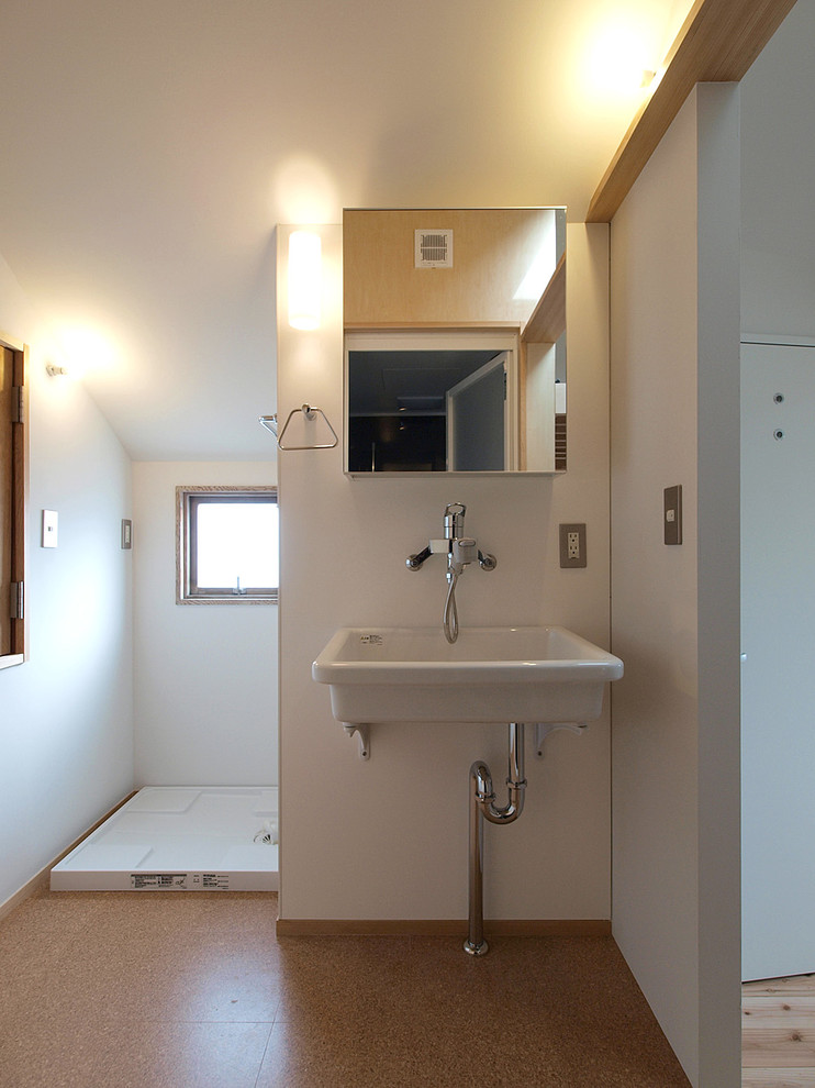 На фото: туалет в скандинавском стиле с белыми стенами, пробковым полом и коричневым полом с