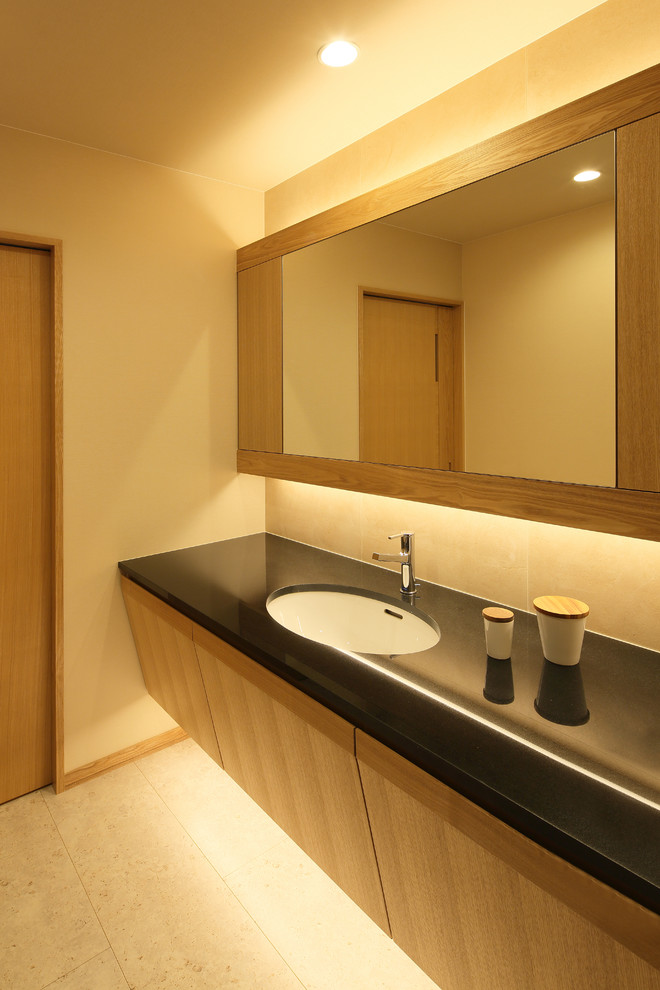 Foto på ett orientaliskt toalett, med släta luckor, skåp i mellenmörkt trä, beige väggar, ett nedsänkt handfat och beiget golv