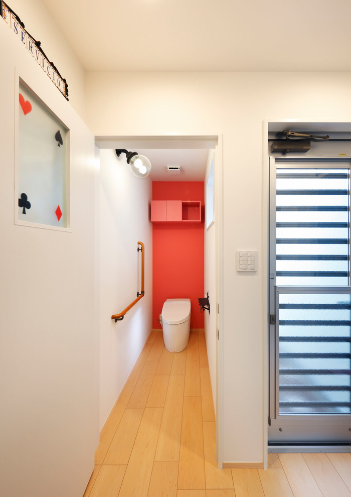 大阪にある北欧スタイルのおしゃれなトイレ・洗面所 (赤い壁、淡色無垢フローリング、ベージュの床) の写真