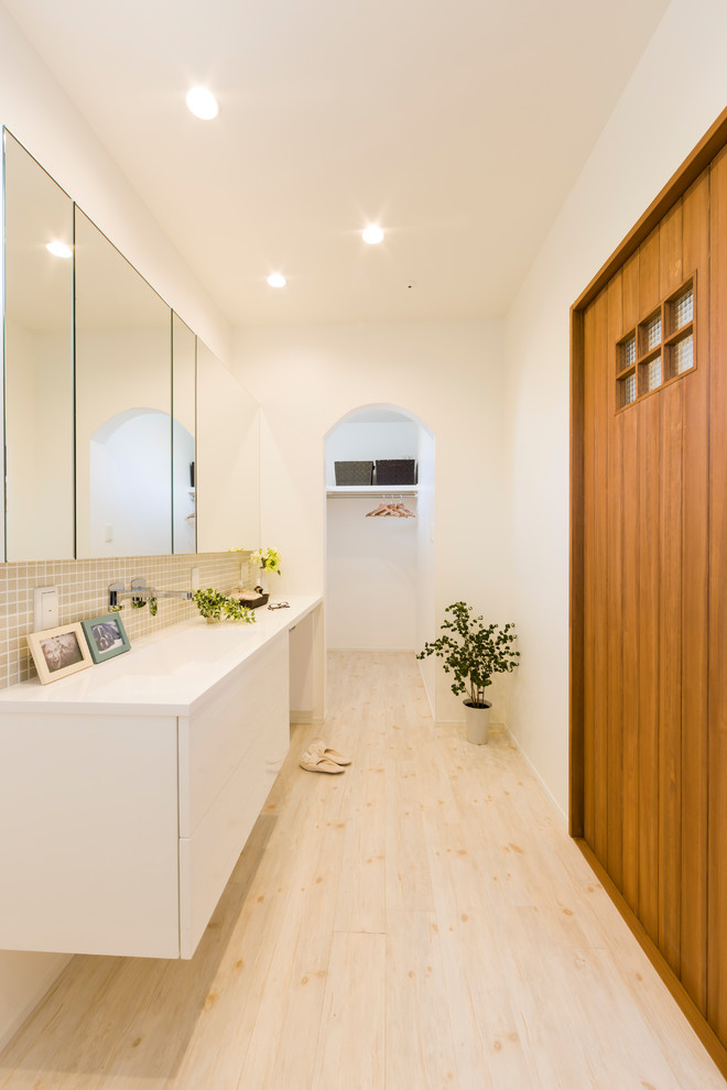 Cette image montre un WC et toilettes rustique avec un carrelage beige, un mur blanc, parquet clair, un sol beige et un plan de toilette blanc.