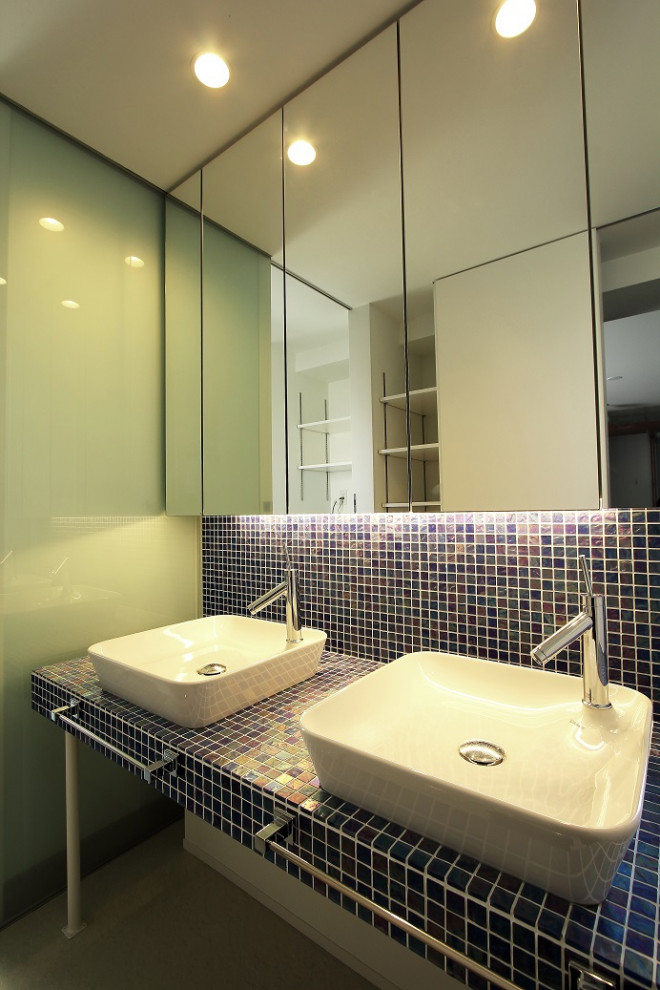 На фото: туалет среднего размера в стиле модернизм с открытыми фасадами, синими фасадами, синей плиткой, белыми стенами, накладной раковиной, столешницей из плитки, синей столешницей и встроенной тумбой