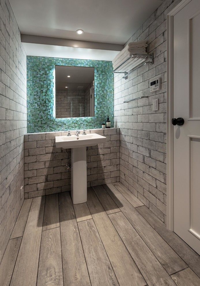 Moderne Gästetoilette mit grauer Wandfarbe, gebeiztem Holzboden, Waschtischkonsole und grauem Boden