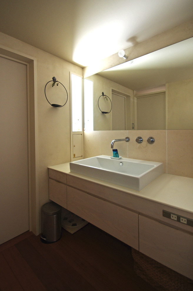 На фото: туалет в стиле фьюжн с белыми стенами, темным паркетным полом и столешницей из искусственного камня