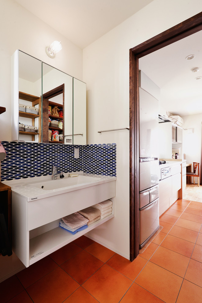 Asiatische Gästetoilette mit offenen Schränken, weißer Wandfarbe, Terrakottaboden, integriertem Waschbecken, orangem Boden und weißer Waschtischplatte in Tokio