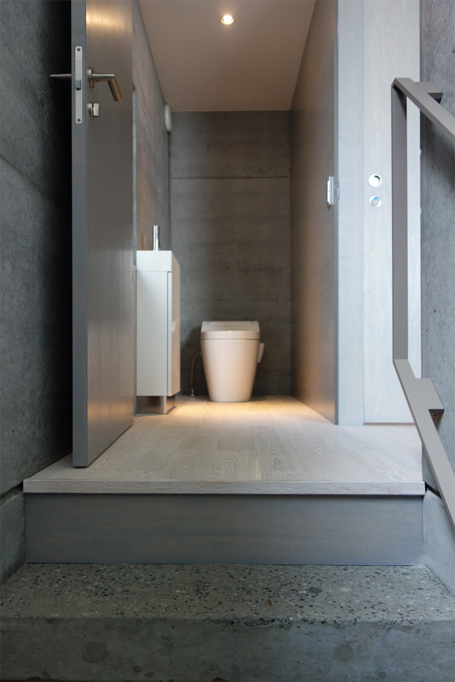 Immagine di un bagno di servizio minimalista con ante a filo, ante bianche, pareti grigie, parquet chiaro, lavabo integrato, top in superficie solida, pavimento bianco e top bianco