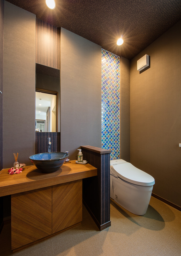 Inspiration for a large traditional cloakroom in Tokyo with freestanding cabinets, dark wood cabinets, a one-piece toilet, blue tiles, mosaic tiles, a console sink, beige floors and grey walls.