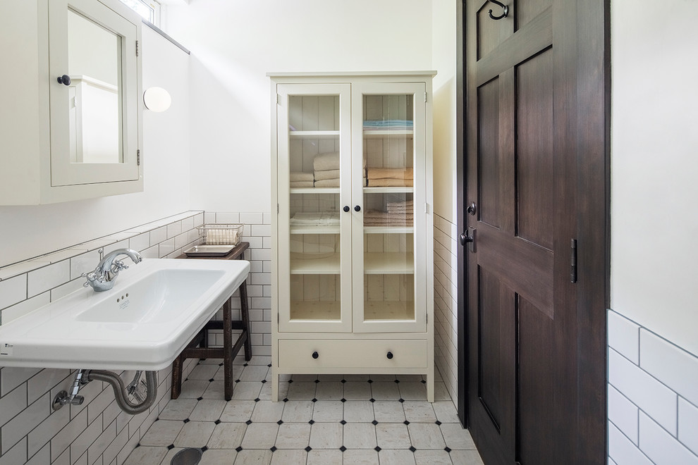 Immagine di un bagno di servizio tradizionale con piastrelle bianche, pareti bianche, lavabo sospeso e pavimento bianco