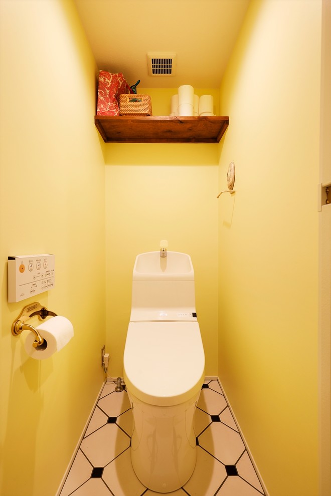 Réalisation d'un WC et toilettes design avec un mur jaune, un sol multicolore et un carrelage jaune.