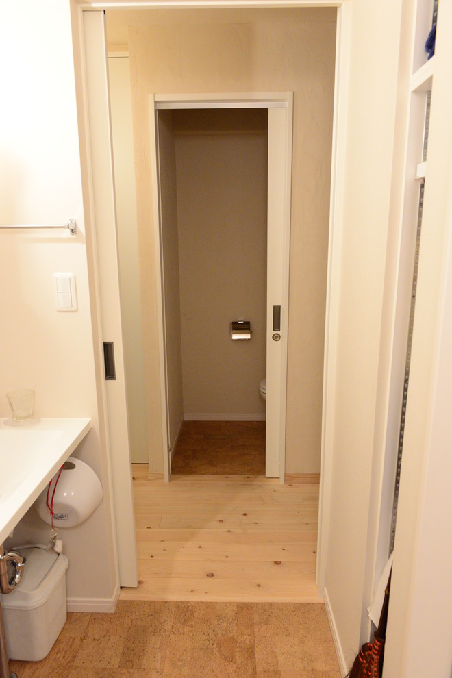 Пример оригинального дизайна: туалет в стиле модернизм с белыми стенами, пробковым полом, столешницей из искусственного камня и коричневым полом