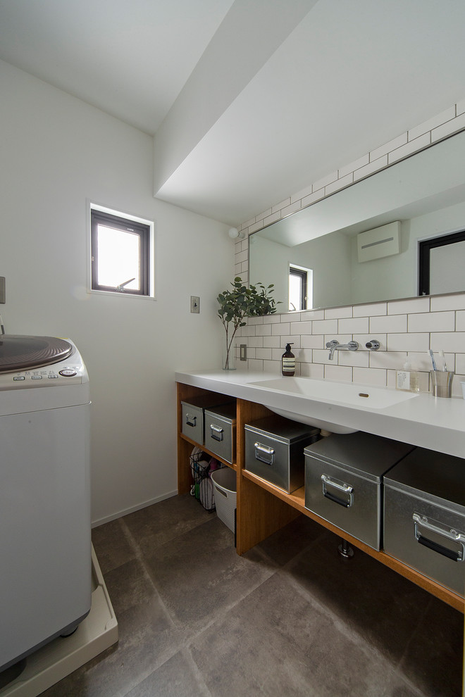 Réalisation d'un WC et toilettes urbain en bois brun de taille moyenne avec un placard sans porte, un carrelage blanc, un carrelage métro, un mur blanc, un lavabo intégré, un plan de toilette en surface solide, un sol gris et un plan de toilette blanc.