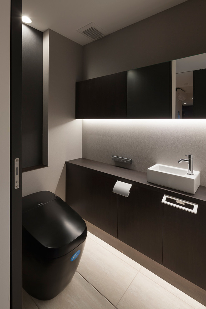 На фото: туалет в стиле модернизм с плоскими фасадами, черными фасадами, разноцветными стенами, настольной раковиной и бежевым полом с