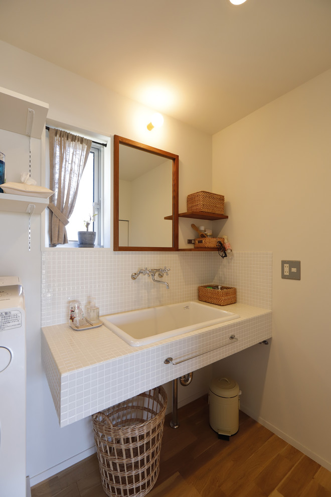 Rural cloakroom in Other with open cabinets, white cabinets, white tiles, porcelain tiles, white walls, medium hardwood flooring, a trough sink, tiled worktops, beige floors, white worktops and a built in vanity unit.