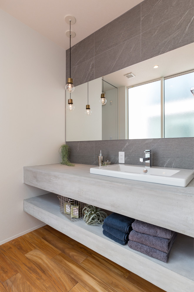 Design ideas for a modern cloakroom in Nagoya with open cabinets, grey cabinets, grey tiles, white walls, medium hardwood flooring, a built-in sink, concrete worktops, brown floors and grey worktops.