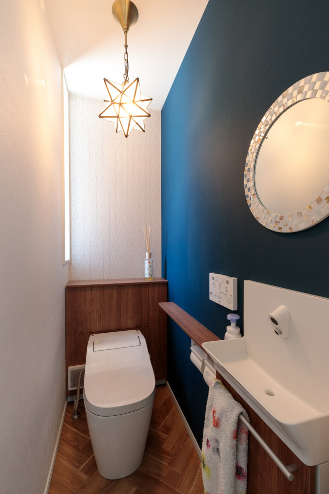 Cette image montre un WC et toilettes minimaliste avec un mur bleu, un sol en bois brun, un plafond en papier peint et du papier peint.