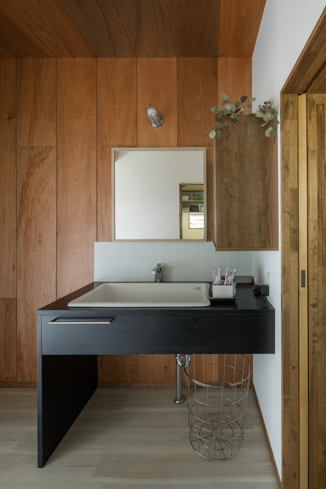 Пример оригинального дизайна: туалет в стиле лофт с коричневыми стенами, деревянным полом, накладной раковиной, серым полом и черной столешницей