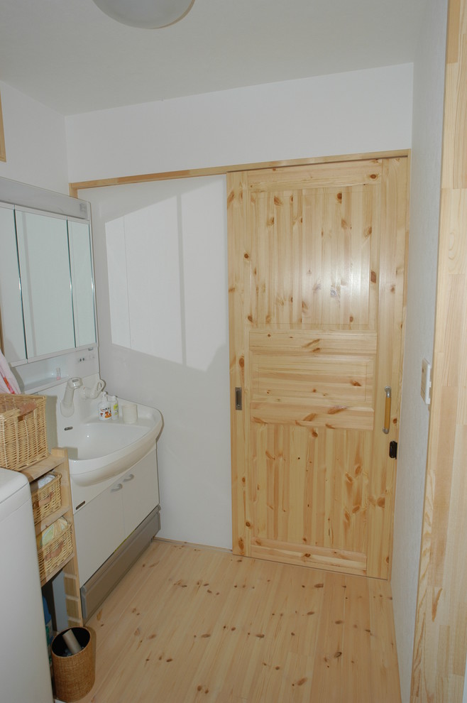 Photo of a medium sized scandinavian cloakroom in Other with flat-panel cabinets, white cabinets, light hardwood flooring and beige floors.