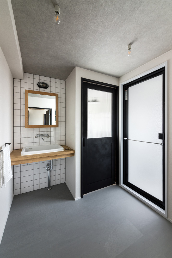Идея дизайна: туалет в стиле лофт с белой плиткой, керамогранитной плиткой, белыми стенами, накладной раковиной и столешницей из дерева
