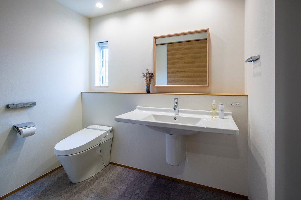 Immagine di un bagno di servizio moderno con WC monopezzo, pareti bianche, pavimento grigio e top bianco