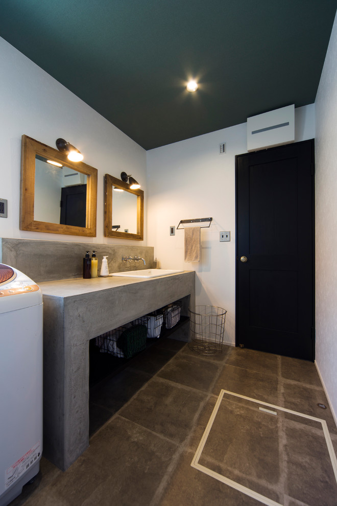 Cette photo montre un WC et toilettes rétro avec un placard sans porte, un mur blanc, un lavabo posé, un plan de toilette en béton et un sol gris.
