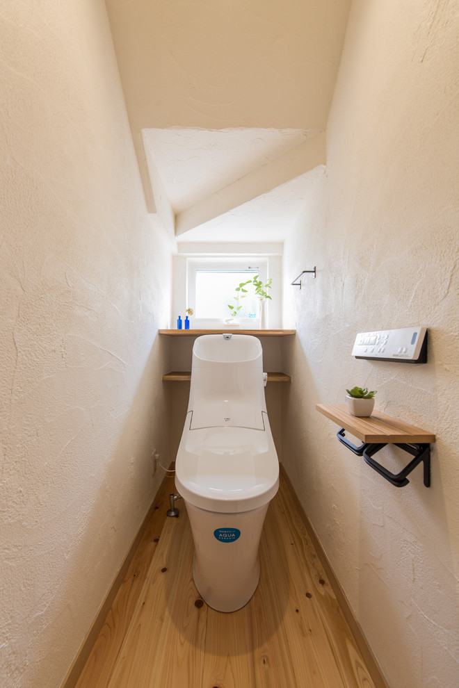 Idée de décoration pour un WC et toilettes asiatique avec un mur blanc, un sol en bois brun et un sol marron.