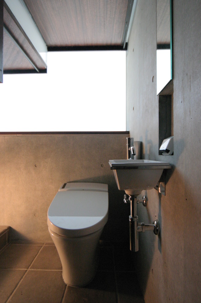 На фото: туалет в стиле модернизм с стеклянными фасадами, унитазом-моноблоком, серыми стенами, пробковым полом, накладной раковиной, столешницей из дерева и коричневым полом с