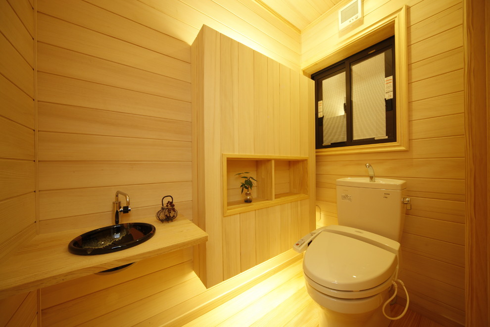 Идея дизайна: туалет среднего размера в современном стиле с фасадами островного типа, светлыми деревянными фасадами, унитазом-моноблоком, бежевой плиткой, бежевыми стенами, светлым паркетным полом, накладной раковиной, столешницей из дерева, бежевым полом и бежевой столешницей