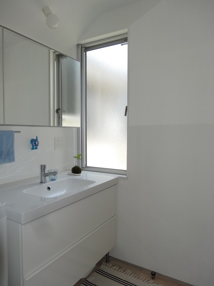 Esempio di un bagno di servizio moderno di medie dimensioni con ante bianche, piastrelle bianche, pareti bianche, pavimento in legno massello medio, lavabo integrato, pavimento beige e top bianco