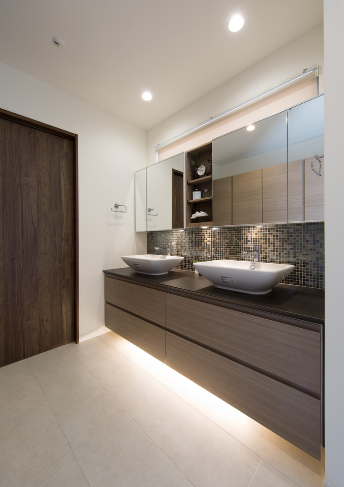 This is an example of a modern cloakroom in Yokohama with white walls, a vessel sink and beige floors.