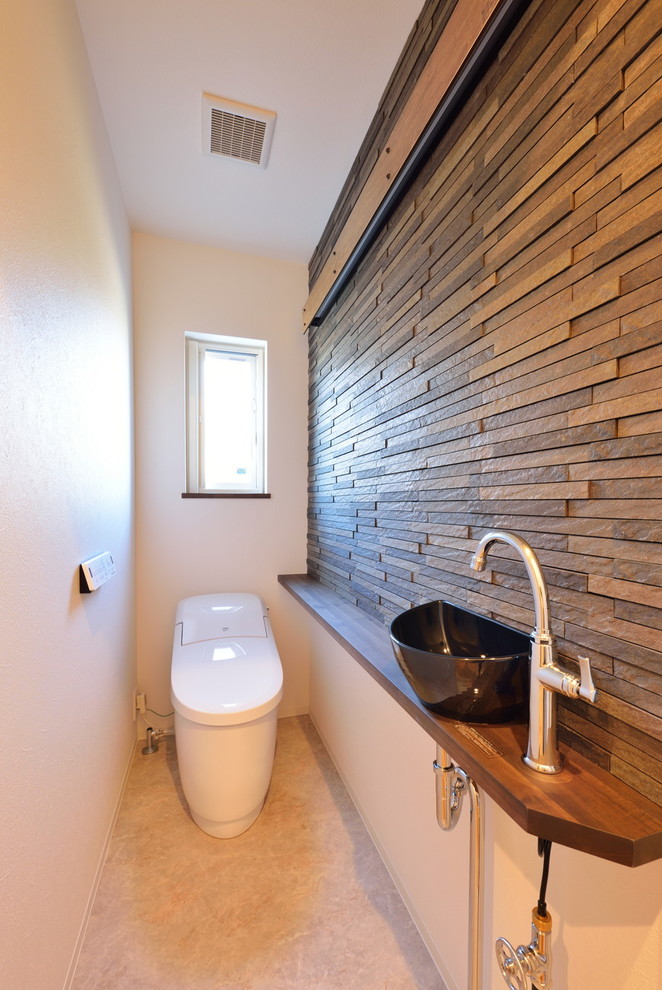 Idée de décoration pour un WC et toilettes vintage avec un mur multicolore, une vasque, un plan de toilette en bois, un sol beige et un plan de toilette marron.