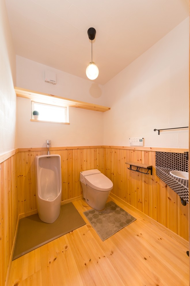 Asiatische Gästetoilette mit weißer Wandfarbe, braunem Holzboden, Waschtischkonsole und braunem Boden in Sonstige