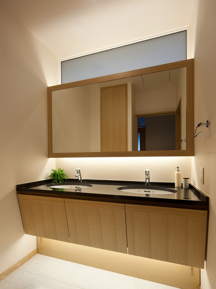 Esempio di un bagno di servizio etnico con pareti beige, lavabo da incasso e pavimento bianco