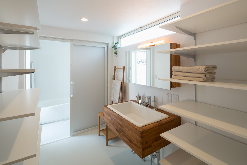 Diseño de aseo moderno con armarios abiertos, puertas de armario blancas, paredes blancas y encimera de madera