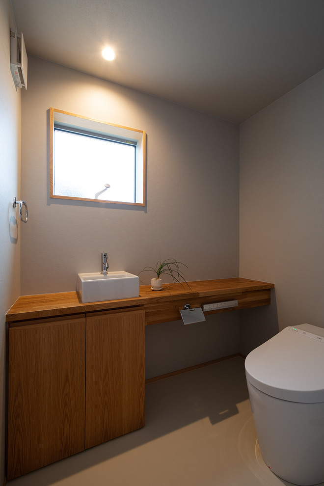 他の地域にあるアジアンスタイルのおしゃれなトイレ・洗面所 (インセット扉のキャビネット、中間色木目調キャビネット、青い壁、木製洗面台、白い床、ブラウンの洗面カウンター) の写真