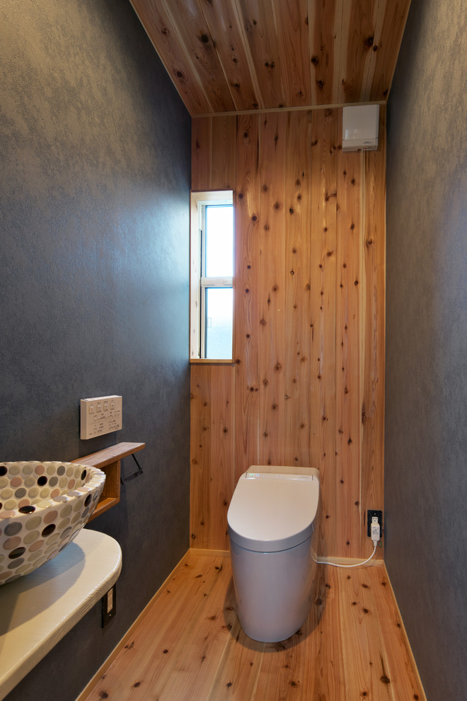 Stilmix Gästetoilette mit bunten Wänden, braunem Holzboden, Aufsatzwaschbecken und braunem Boden in Sonstige