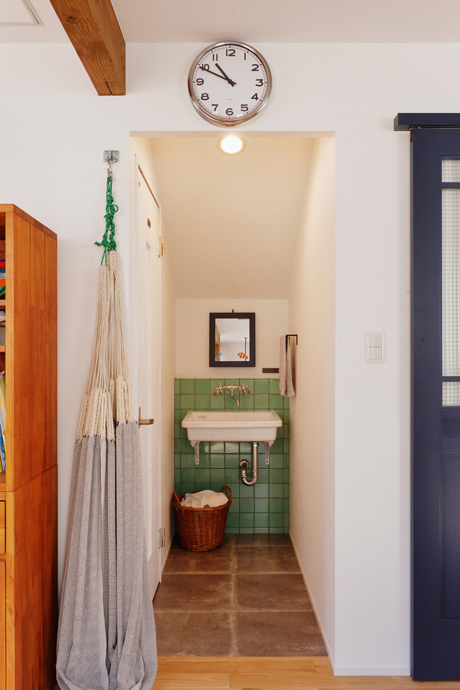 Идея дизайна: туалет в стиле лофт с зеленой плиткой, полом из терракотовой плитки, консольной раковиной и коричневым полом