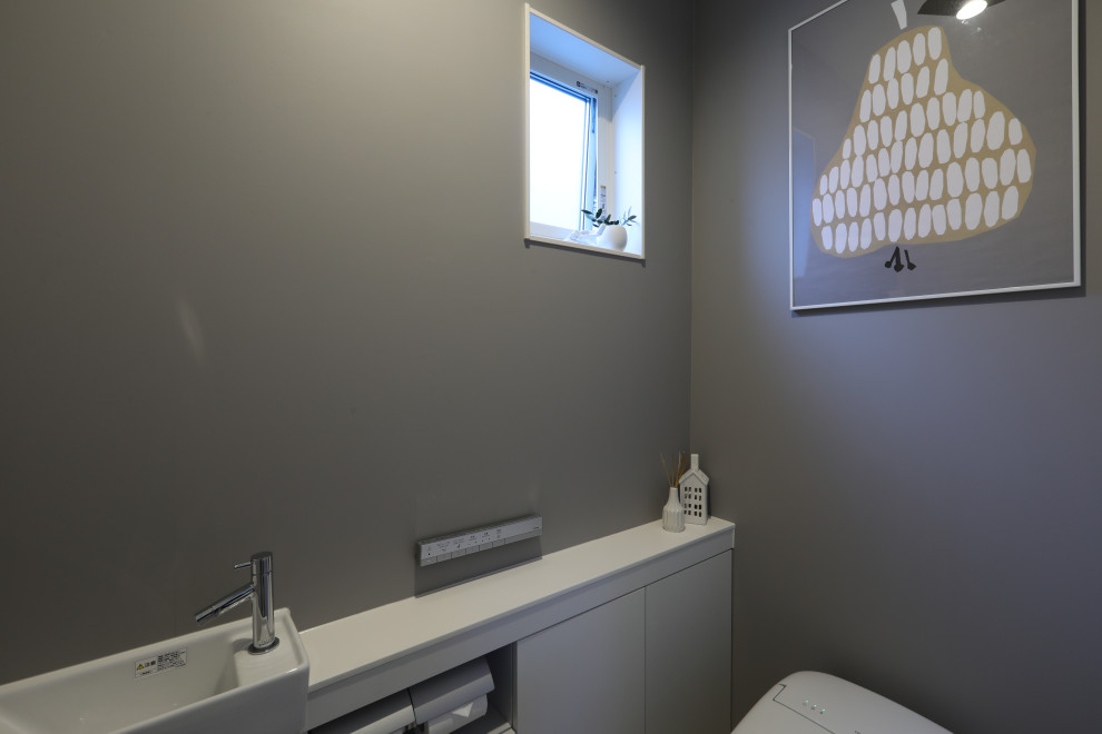 Inspiration pour un WC et toilettes minimaliste de taille moyenne avec des portes de placard blanches, WC à poser, un mur gris, un sol en vinyl, un sol multicolore et un plan de toilette blanc.