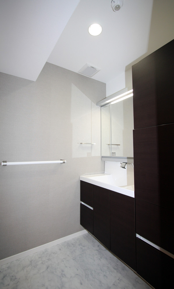 Mittelgroße Moderne Gästetoilette mit flächenbündigen Schrankfronten, dunklen Holzschränken, weißer Wandfarbe, Marmorboden, integriertem Waschbecken und Mineralwerkstoff-Waschtisch in Tokio