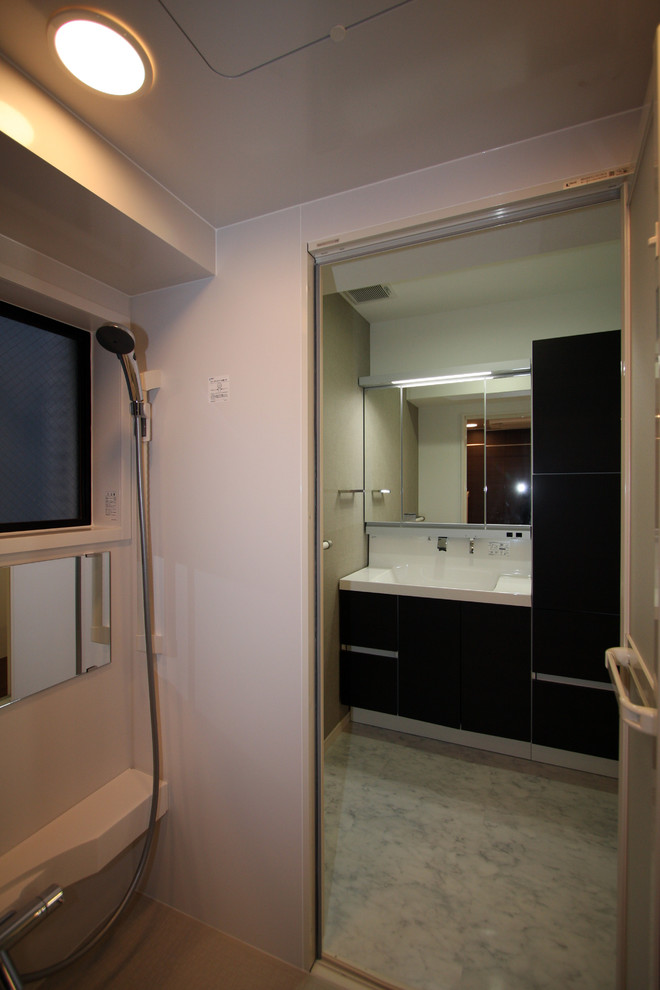 Idee per un bagno di servizio minimalista di medie dimensioni con ante lisce, ante in legno bruno, pareti bianche, pavimento in marmo, lavabo integrato e top in superficie solida