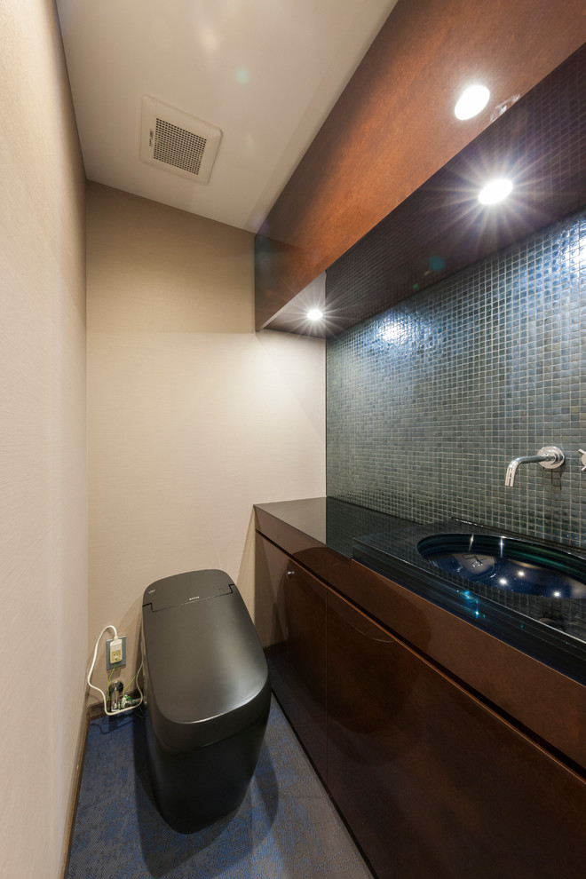 Moderne Gästetoilette mit flächenbündigen Schrankfronten, hellbraunen Holzschränken, beiger Wandfarbe, integriertem Waschbecken und blauem Boden in Tokio