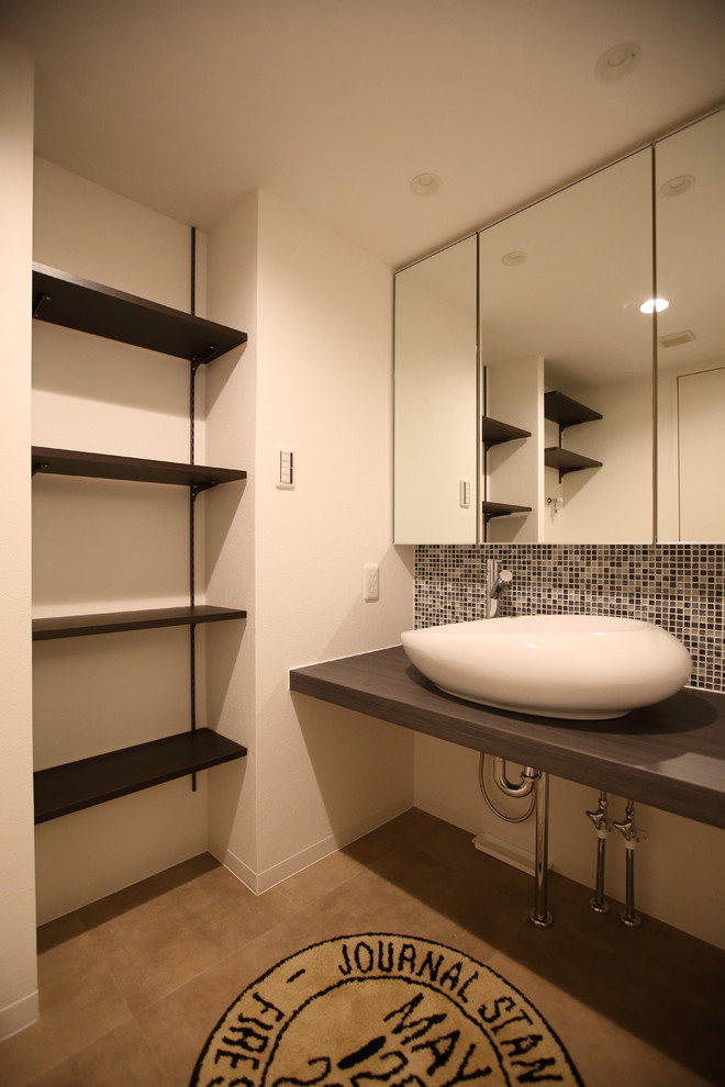 Cette image montre un petit WC et toilettes avec un carrelage noir et blanc, mosaïque, un mur blanc, un sol en carrelage de céramique et une vasque.