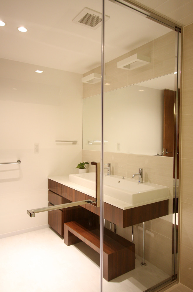 東京23区にある高級な中くらいなコンテンポラリースタイルのおしゃれなトイレ・洗面所 (フラットパネル扉のキャビネット、濃色木目調キャビネット、ベージュのタイル、セラミックタイル、白い壁、クオーツストーンの洗面台、オーバーカウンターシンク、白い床、リノリウムの床) の写真