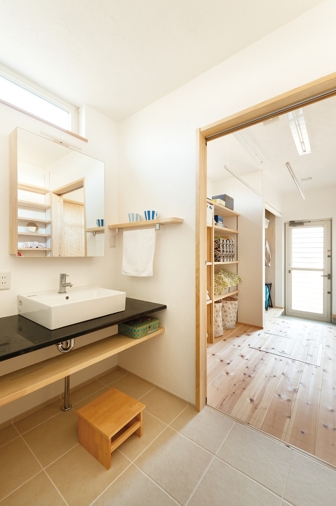 Photo of a world-inspired cloakroom in Other with open cabinets, white walls, a vessel sink and grey floors.