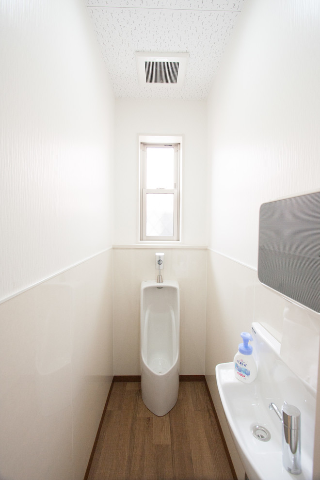 Réalisation d'un petit WC et toilettes minimaliste en bois brun avec un mur blanc, un sol en contreplaqué, un lavabo intégré, un plan de toilette en surface solide et un sol blanc.