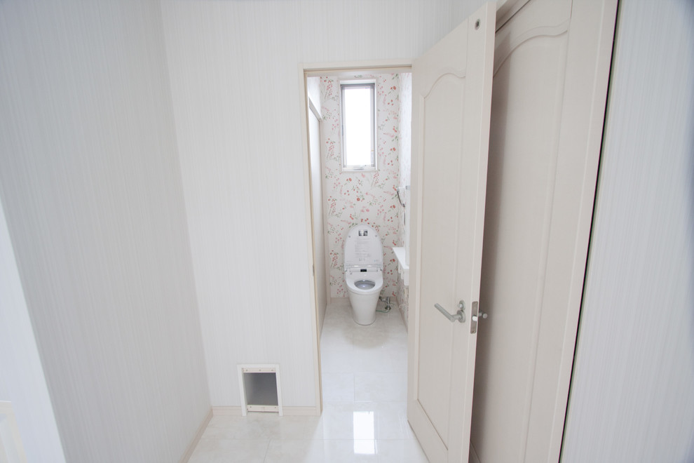 Cette image montre un WC et toilettes minimaliste de taille moyenne avec un mur blanc, un sol en contreplaqué et un sol blanc.